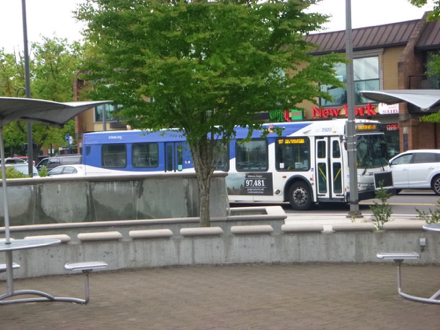TriMet bus stop at Tualatin Library - brick surface in front of library - tables, seats and umbrellas